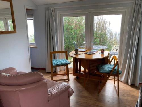a living room with a table and chairs and a window at Cliff top Chalet with fantastic sea views in Cornwall. in Cawsand