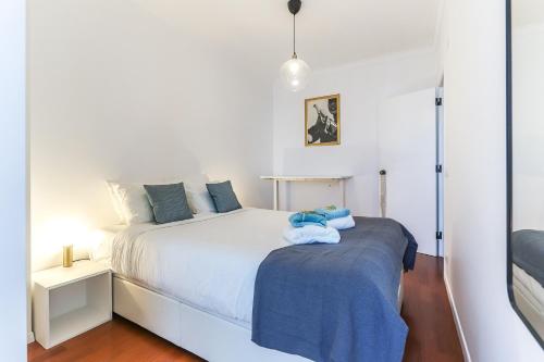 a bedroom with a white bed with a blue blanket at Vita Portucale ! Surf Concept Costa Caparica in Costa da Caparica