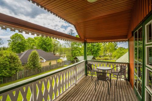 a wooden deck with a table and chairs on it at Alaušo Salos - Malinauskų kaimo turizmo sodyba in Sudeikiai