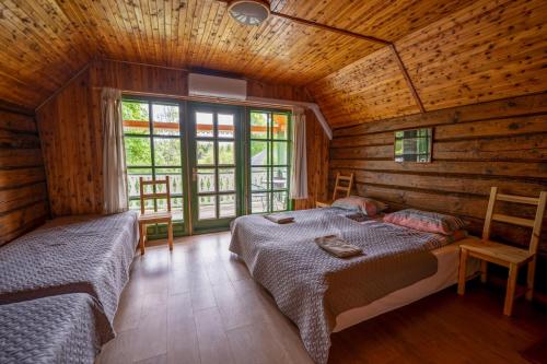 1 dormitorio con 2 camas en una cabaña de madera en Alaušo Salos - Malinauskų kaimo turizmo sodyba, en Sudeikiai