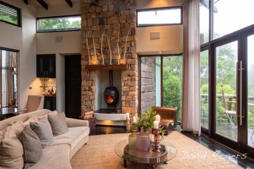 a living room with a couch and a fireplace at Tsala Treetop Lodge in Plettenberg Bay
