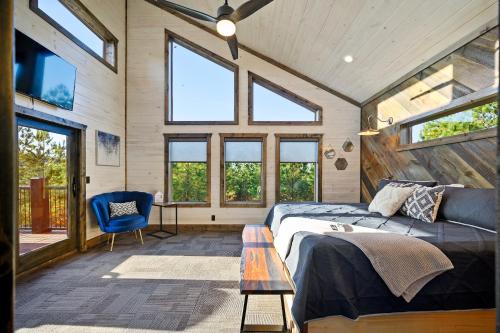 a bedroom with a bed and a table and windows at All FORE The View Cabin in Hochatown in Broken Bow