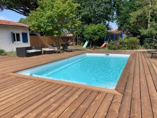 a swimming pool on a wooden deck with a swimming poolvisor at Le Chêne Vert - Grande Villa familiale avec piscine - Bassin d'Arcachon in Arès