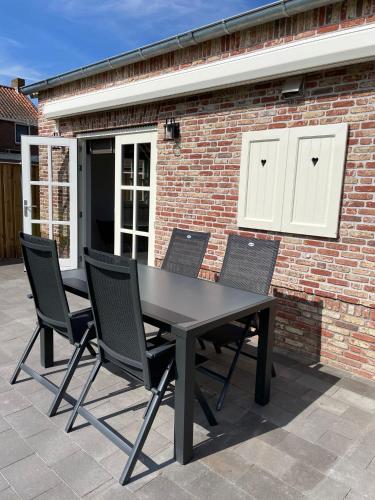 a black table and chairs in front of a brick building at Vakantiewoning De Krab in Sint Annaland