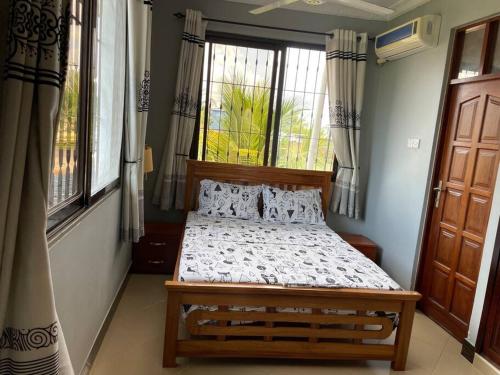 a bedroom with a bed in a room with windows at Cheerful studio apartment in Dar es Salaam