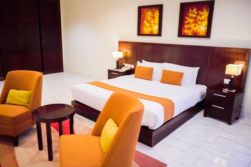 a hotel room with a bed and two chairs at City Seasons Hotel & Suites Muscat in Muscat