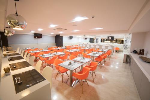 a dining room with tables and orange chairs at Intercity Campina Grande Citymix in Campina Grande