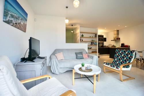 ein Wohnzimmer mit einem Sofa und einem TV in der Unterkunft Le Clos de l'Anse *front de mer* in Ploemeur