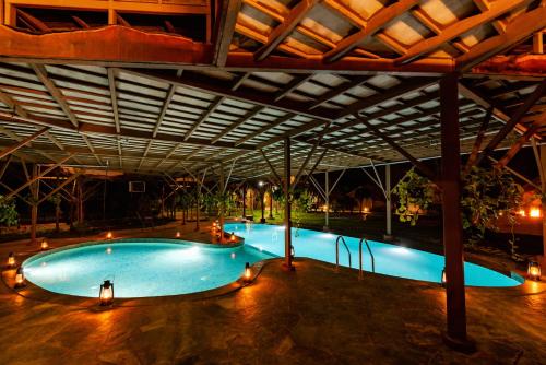 a large swimming pool in a building at night at Tadoba Jungle Camp in Mohurli