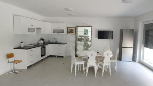 uma cozinha com armários brancos e uma mesa e cadeiras em Haus mit Garten bei Wien em Langenzersdorf