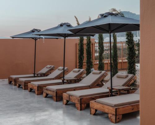 a row of lounge chairs and umbrellas on a patio at Aerope SeaView Villa in Koutsounari