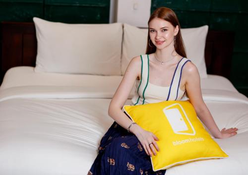 a woman sitting on a bed holding a yellow pillow at Bloom Boutique - Chelon Haveli in Jaipur