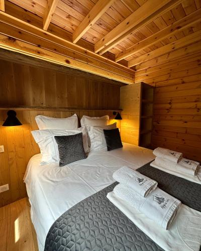 uma cama grande num quarto com paredes de madeira em Chalet Le Familial - SPA & SAUNA - Serviettes - Peignoirs - Lits faits - Ménage inclus em Rochesson