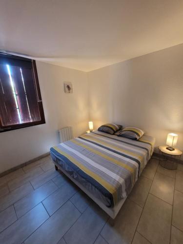 a bedroom with a bed with two lamps and a window at COLLIOURE tres bel appart a 150 metres des plages avec jardin prive et parking dans residence securisee in Collioure