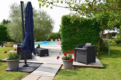 een patio met een parasol en een zwembad bij Gîte l'Ostalet de Sarron à Brax, Lot et Garonne in Brax