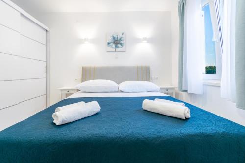 een bed met twee witte handdoeken op een blauwe deken bij Apartment Blue in Makarska