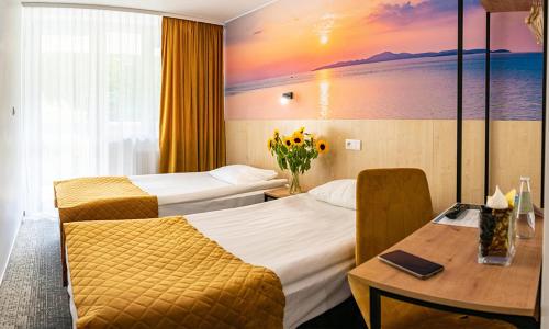 um quarto de hotel com duas camas e uma mesa com flores em Centrum Konferencyjno Rekreacyjne Molo em Smardzewice