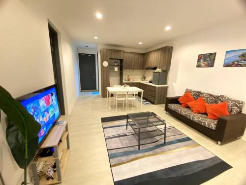een woonkamer met een bank en een flatscreen-tv bij Rehat Guest House, The Square, One City, USJ25 in Subang Jaya