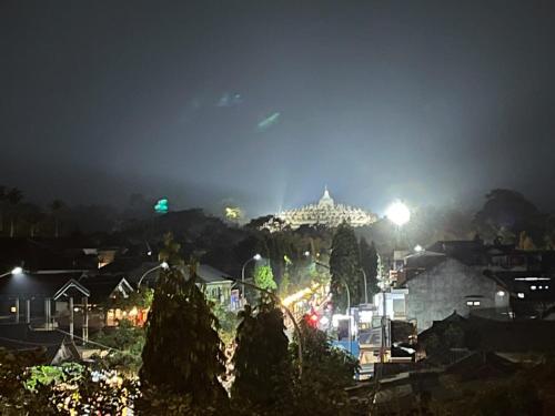 una ciudad iluminada por la noche con un edificio en el fondo en Omahku Homestay, en Borobudur