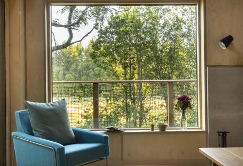 a blue chair sitting in front of a large window at Mertrick in Forest Mill