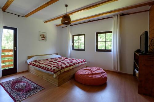 een slaapkamer met een bed en een poef erin bij Susurul Apei Chalet in Porumbacu de Sus