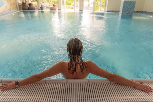 Robenstein Hotel & SPA - Villa في تزفيسل: امرأة ترتدي البكيني جالسة في حمام السباحة