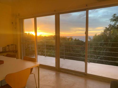 Habitación con ventana grande con vistas a la puesta de sol. en 青の洞窟 'Blue in Green' 青の洞窟が目の前のコテージ! Ocean view & 満天の星! 広々セミダブルベッド, en Ishigaki Island