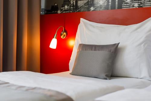 uma cama com almofadas brancas e uma parede vermelha em Hotel Vista em Brno
