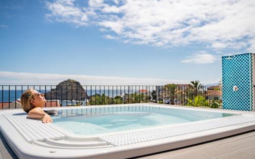 a little girl laying in a hot tub on a balcony at Studios by Aqua Natura Hotels in Porto Moniz