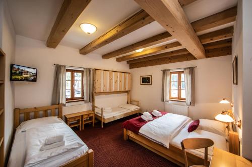 two beds in a room with wooden ceilings at Pivovar Lyer in Modrava