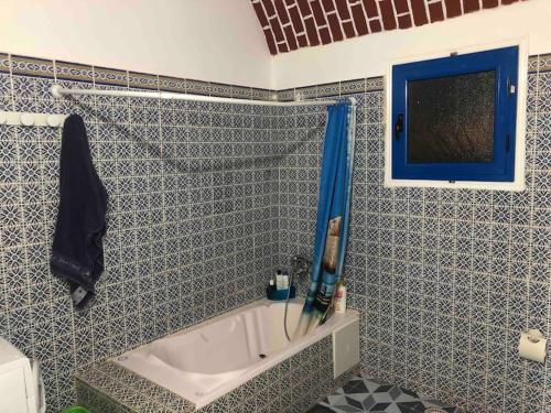 ein Bad mit einer Badewanne an einer blau-weißen Wand in der Unterkunft Appartement MANEL in Mezraya