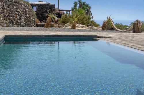 a swimming pool with blue water in front of a house at Agriturismo Zibibbodoro in Pantelleria