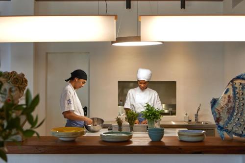two chefs standing in a kitchen preparing food at Hotel Tres Torres in Santa Eularia des Riu