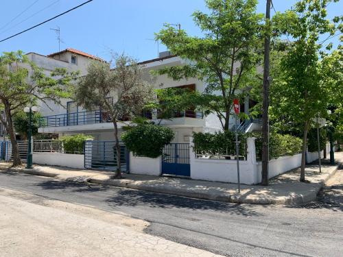 a white building with trees in front of a street at Blue Maison in Paralia Katerinis
