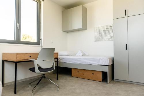 um quarto com uma secretária, uma cama e uma cadeira em Hostel 'SD Palacin' em Sibenik