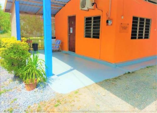 uma casa laranja com um alpendre e um pátio em ROOMSTAY SHAHID HOU'ZE em Kangar