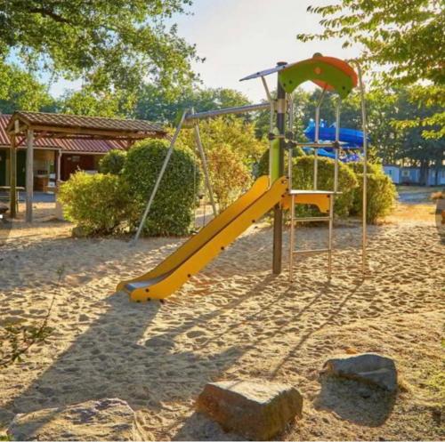 une aire de jeux avec toboggan jaune dans un parc dans l'établissement Camping Tohapi Coeur de Vendée, à La Boissière-de-Montaigu