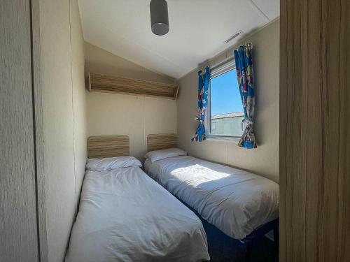 two beds in a small room with a window at Lovely 6 Berth Caravan At Valley Farm Park In Essex Ref 46762v in Great Clacton
