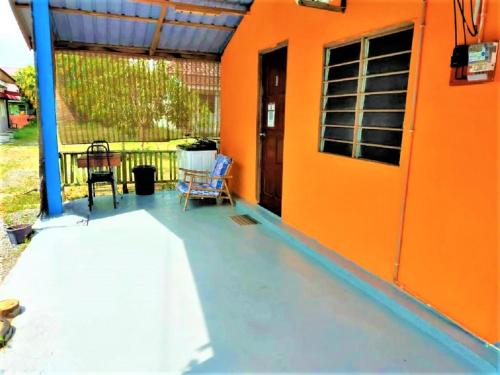 uma casa laranja com uma mesa e cadeiras num pátio em ROOMSTAY SHAHID HOU'ZE em Kangar