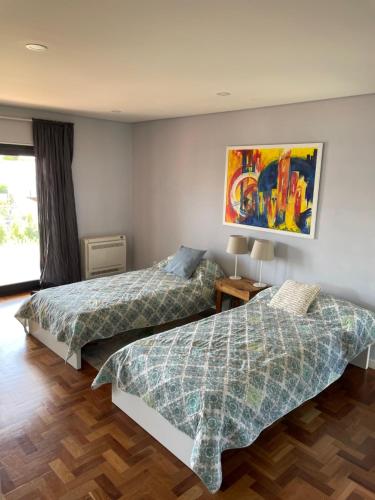 two beds in a room with a painting on the wall at Casa em Cascais in Cascais
