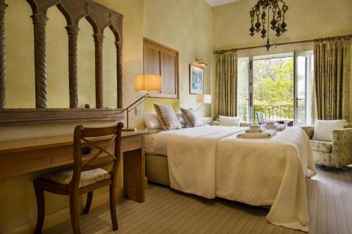 a bedroom with a bed and a desk and a mirror at Yewfield Vegetarian Guest house in Ambleside