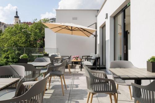 a patio with tables and chairs and an umbrella at Aparthotel Na Klenici in Mladá Boleslav