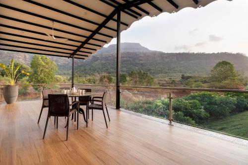a dining room with a table and chairs and a view at SaffronStays Sanvina Farm, Karjat in Karjat