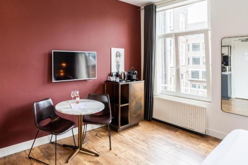 Zimmer mit einem Tisch und Stühlen sowie einem TV in der Unterkunft Weber Hotel 397 in Amsterdam