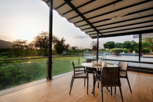 a dining room with a table and chairs and a large window at SaffronStays Sanvina Farm, Karjat in Karjat