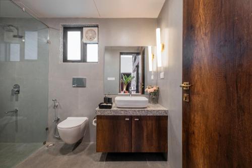 a bathroom with a sink and a toilet and a mirror at SaffronStays Sanvina Farm, Karjat in Karjat