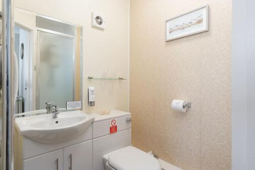 Baño blanco con lavabo y aseo en Room 3 Hotel style Double bedroom in Marazion en Marazion