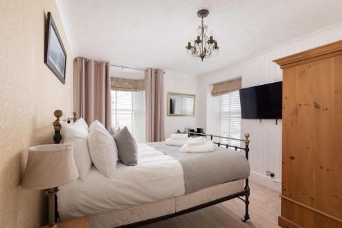 Un dormitorio con una cama con sábanas blancas y una lámpara de araña. en Room 3 Hotel style Double bedroom in Marazion en Marazion