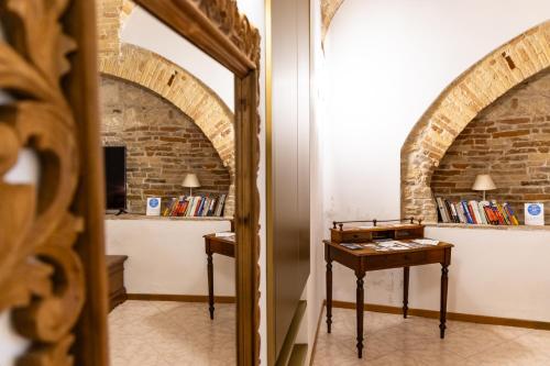 a mirror in a room with a table and a brick wall at La Rua in Ascoli Piceno
