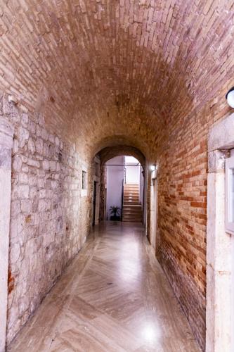 an alley way in a brick wall with a tunnel at La Rua in Ascoli Piceno